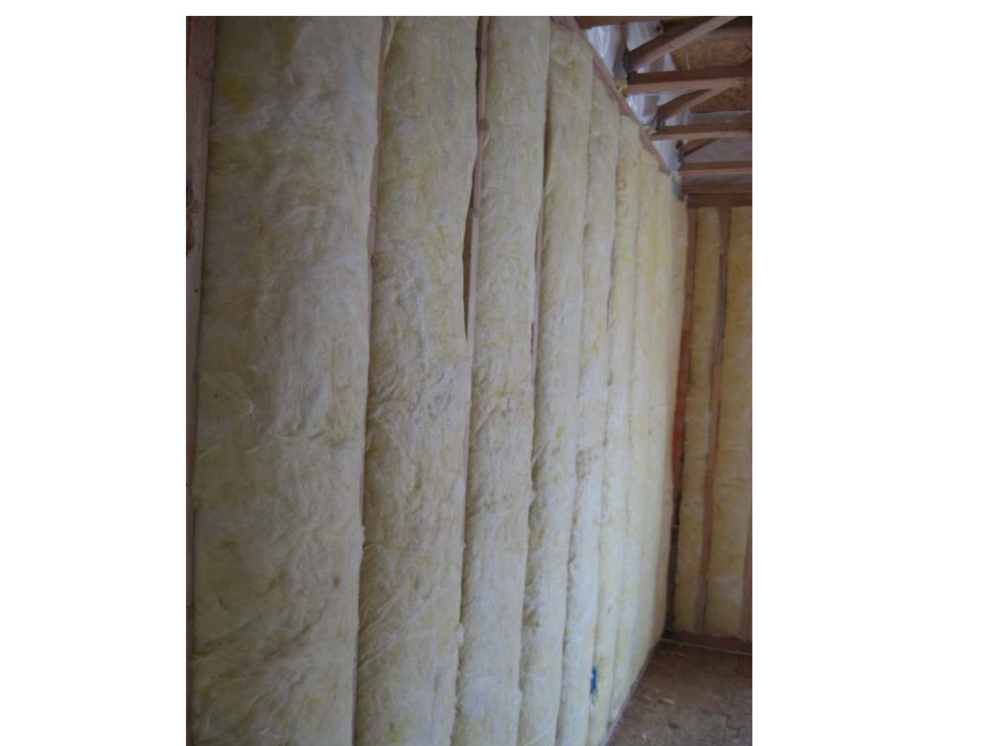 Unfaced fiberglass batts filling wall cavities completely, split around wiring