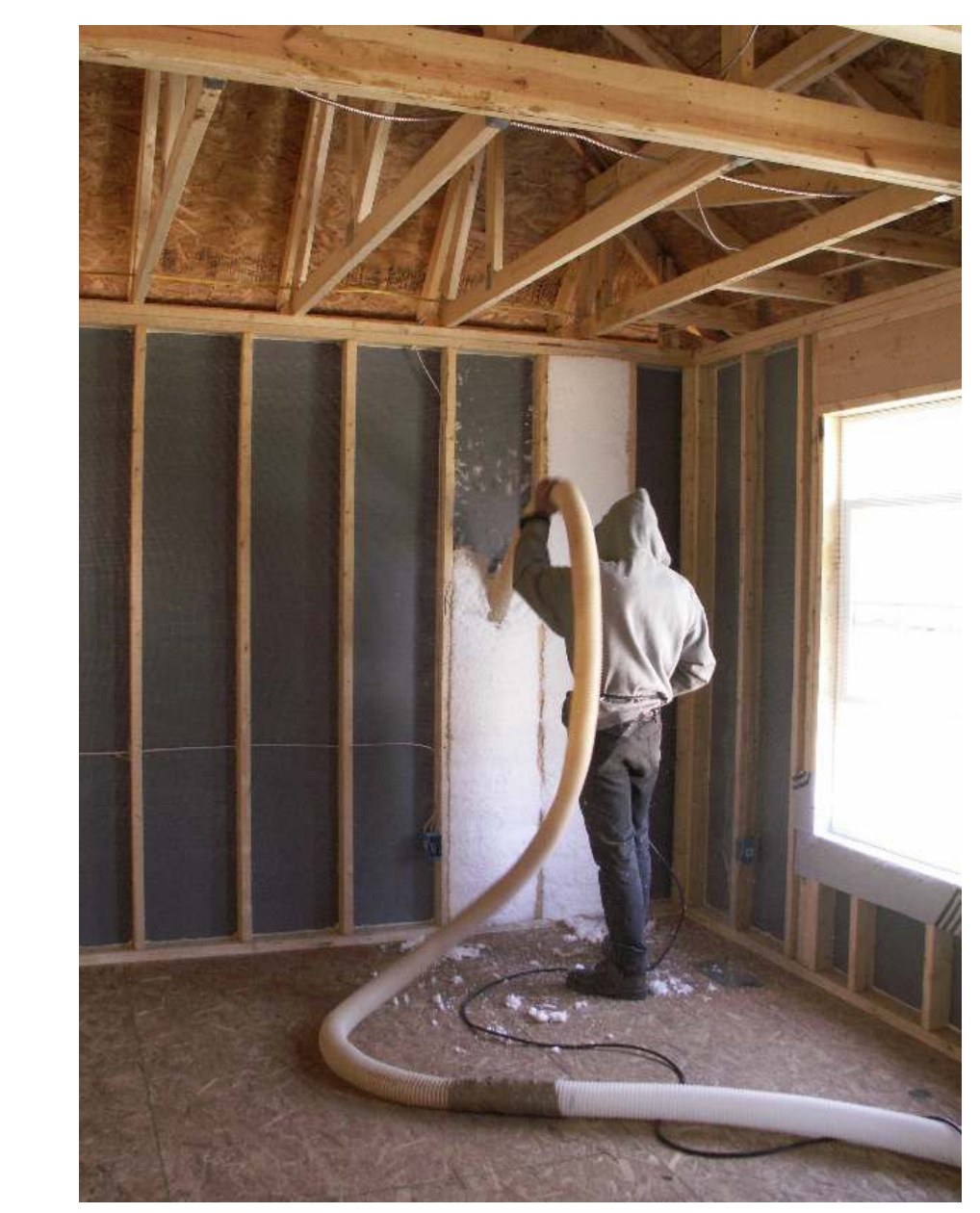 Blown fiberglass filling netted wall cavities around wiring